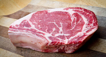 Thick Bone-In Rib Eye Steak on a cutting board Thick Bone-In Rib Eye Steak on a cutting board